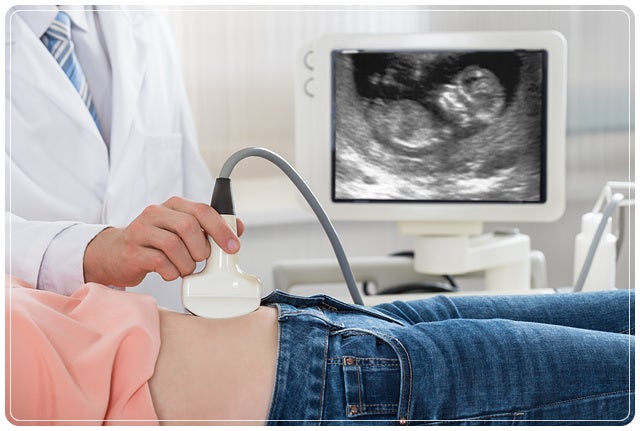 의사가 환자 복부에 초음파 프로브를 대고 검사하며 모니터에 태아 초음파 영상이 표시된 장면