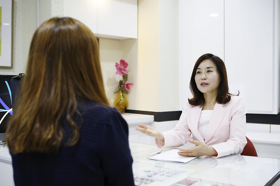 핑크색 재킷을 입은 원장이 환자와 진료실 책상에서 상담하는 다른 컷 사진